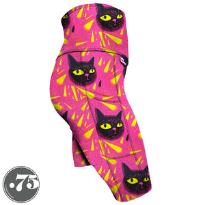 High-waisted, spandex Knee Length pocket shorts. The fabric has a bright pink background with yellow triangle shapes and large hand drawn cat heads with yellow eyes.