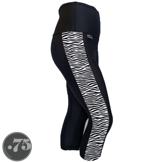 A pair of black spandex capri leggings against a white background. The leggings are calf length and have a panel on the side with a pocket, the panel has fabric that is white with black zebra print horizontally across the panel.