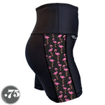 Load image into Gallery viewer, A pair of black spandex shorts against a white background. The shorts are short with a 5” inseam and have a panel on the side with a pocket, the panel has fabric with a charcoal grey background with scattered cartoon pink flamingos on it.
