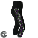 Load image into Gallery viewer, A pair of black spandex capri leggings on a mannequin, the leggings have a 3.5” wide stripe down the side that has a printed fabric with rollerskates, helmets, stars &amp; knee pads. The graphics are in the colours of the Genderqueer Pride Flag green, purple and white. 
