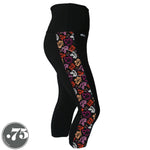 Load image into Gallery viewer, A pair of black spandex capri leggings on a mannequin, the leggings have a 3.5” wide stripe down the side that has a printed fabric with rollerskates, helmets, stars &amp; knee pads. The graphics are in the colours of the Lesbian Pride Flag Colours orange, light orange, white, light pink and dark pink.
