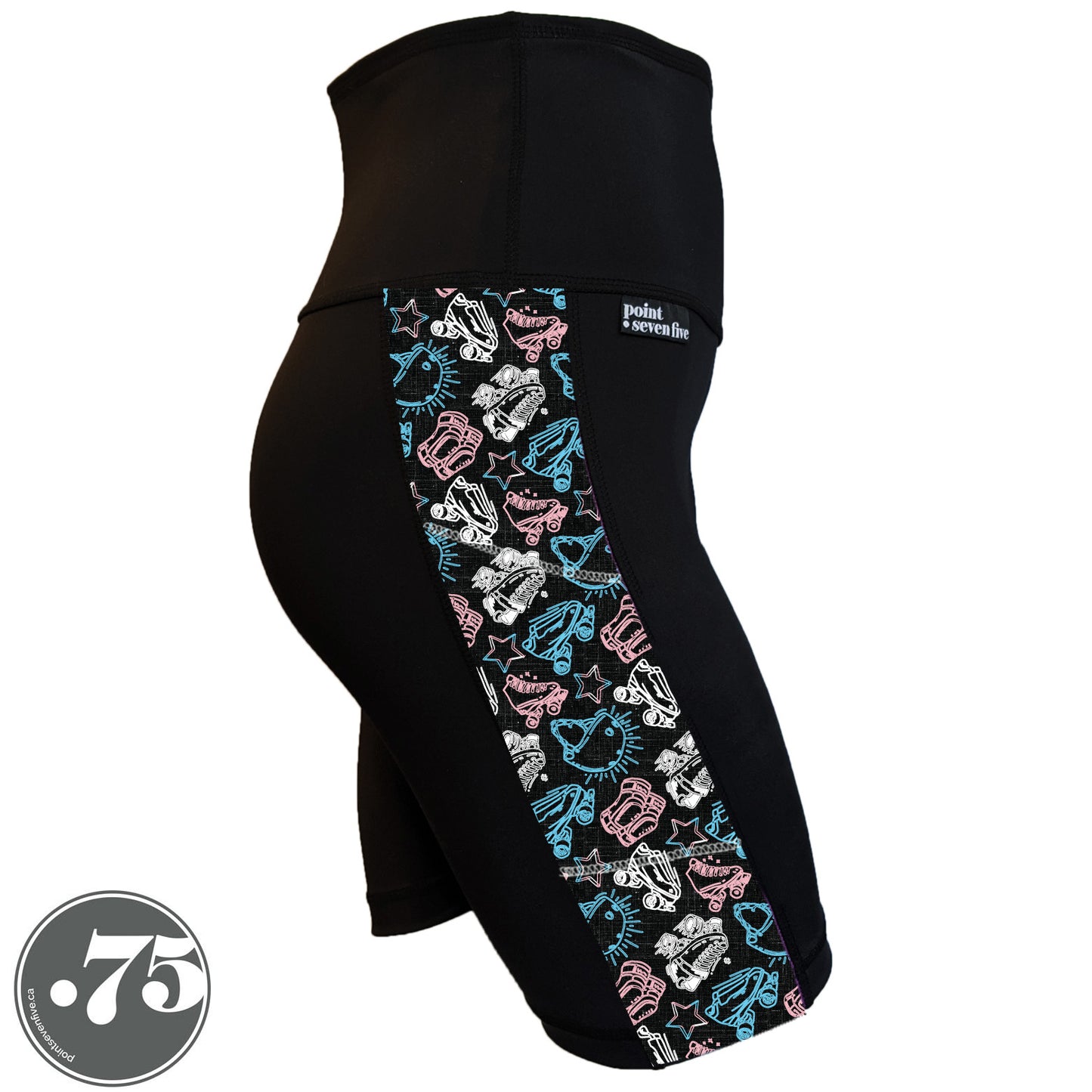 A pair of black spandex skate length shorts on a mannequin, the leggings have a 3.5” wide stripe down the side that has a printed fabric with rollerskates, helmets, stars & knee pads. The graphics are in the colours of the Trans Pride Flag pink, white and light blue.  