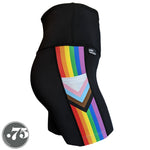 Load image into Gallery viewer, A pair of black spandex lift length shorts on a mannequin, the leggings have a 3.5” wide stripe down the side that has a printed fabric with the stripes of the Progress Pride Flag vertically and the are chevrons placed at the top of the pocket. The stripes are red, orange, yellow, green, blue and purple. The chevrons are white, pink, light blue, brown and black and point down from the top of the pocket.
